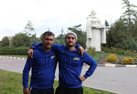Doi hamali HamaL.MD în uniformă pozează lângă un monument alb dintr-un parc din Bălți