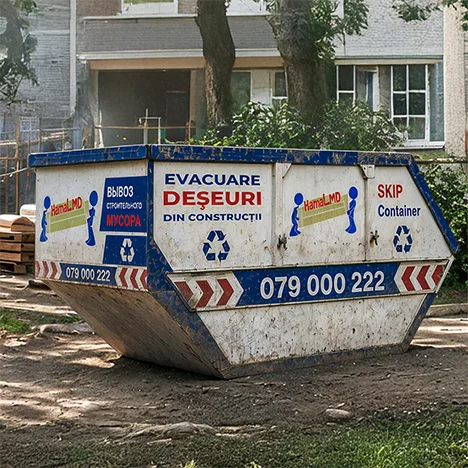 Un container skip metalic este amplasat lângă un bloc pentru deșeuri de construcție
