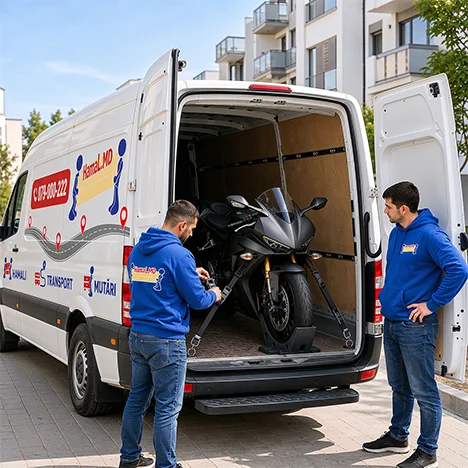 O motocicletă sport este fixată cu chingi și opritor de roată în dubă, iar hamalul verifică legăturile